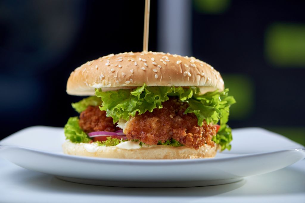 Crispy fried chicken burger with fresh lettuce, red onions, and mayonnaise on a sesame seed bun - Allrecipeworld