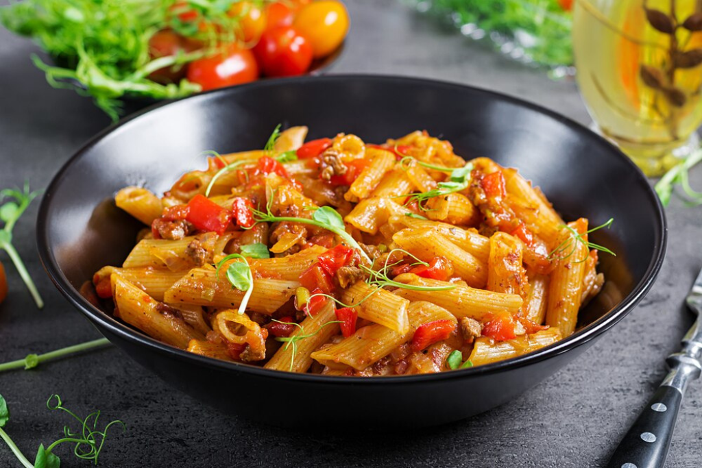 Overhead view of a hearty Beefaroni Recipe served in a white bowl from allrecipeworld, topped with melted cheese and fresh herbs.